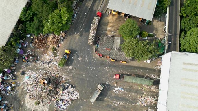 鸟瞰图在环境污染的工业工厂里，不同类型的大型垃圾堆、塑料袋和垃圾车堆积在一起。在倾倒场弃置废物。