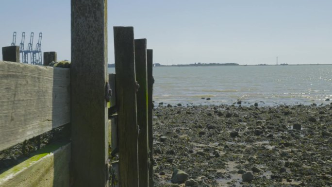 从残迹的码头后面看物流码头。海岸上覆盖着岩石。岩石上长着海藻。