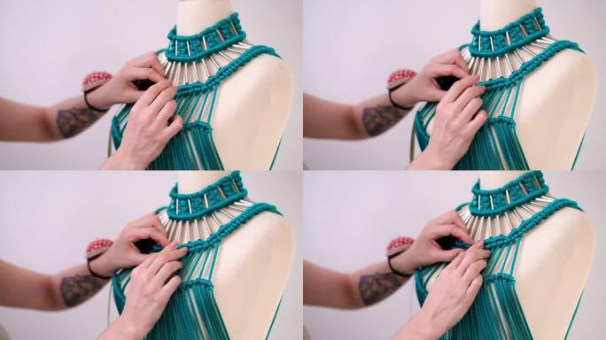 女裁缝在现代时装工作室工作的假人身上系上绿色流苏连衣裙上的结