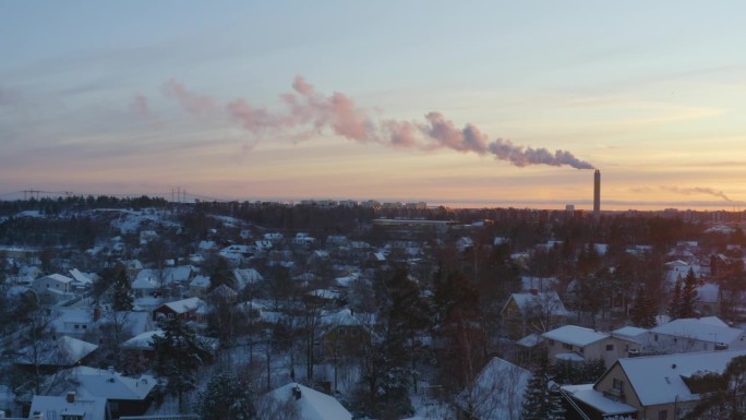 鸟瞰区域供暖设施的烟雾与郊区的白雪皑皑的日落形成对比。