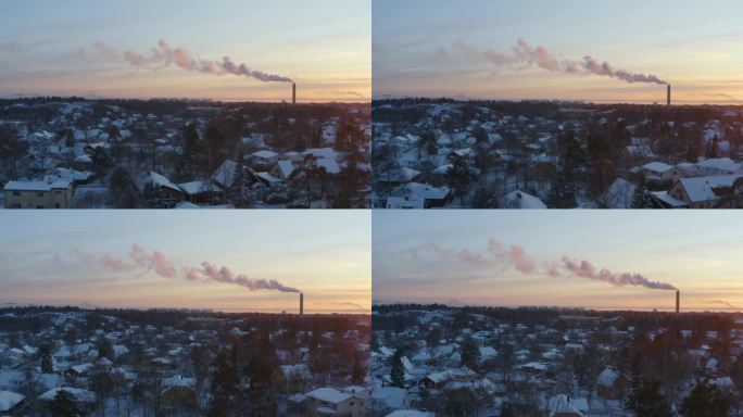 鸟瞰区域供暖设施的烟雾与郊区的白雪皑皑的日落形成对比。