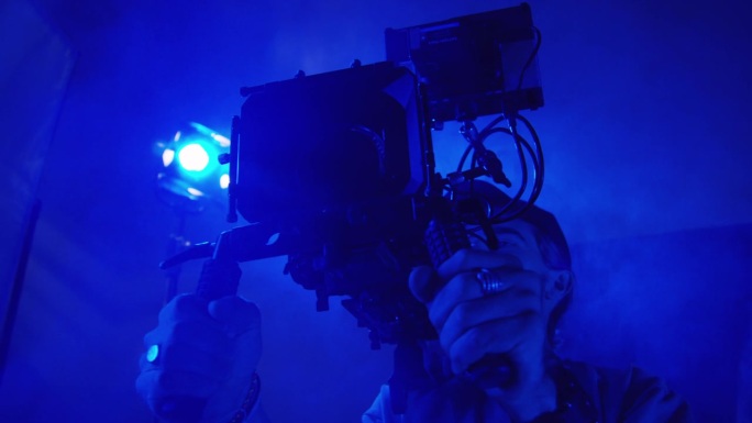 摄影师在蓝光和烟雾中用专业相机拍摄