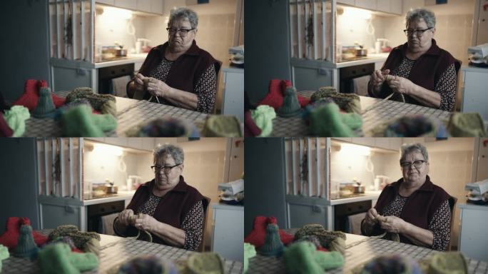 肥胖老年妇女坐在桌边一边自言自语一边在家织毛衣