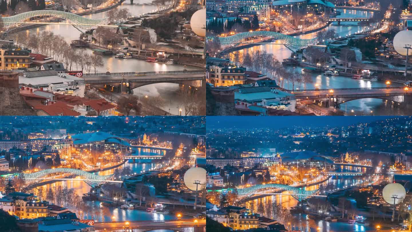 第比利斯,格鲁吉亚。从日落到夜晚，从白天到夜晚的时间过渡。和平之桥风景。夜间照明中著名地标的高架俯视