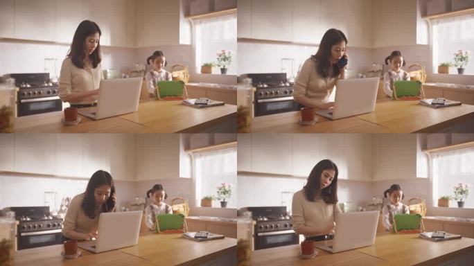 韩国母亲使用笔记本电脑和智能手机在家工作，而她的小女儿使用数码平板电脑。高效的女商人在家办公，成为超