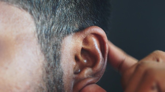 一个耳朵疼的年轻人摸着他疼痛的耳朵，