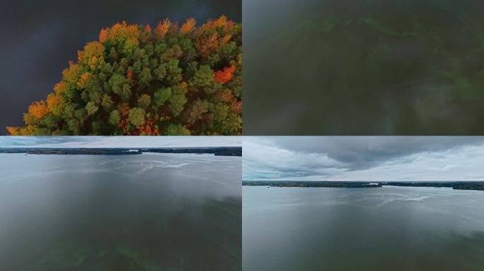 秋季森林的顶部拍摄，绿色，红色，黄色和棕色的树木倾斜，露出一个风景秀丽的蓝藻湖。飞越芬兰Valkea