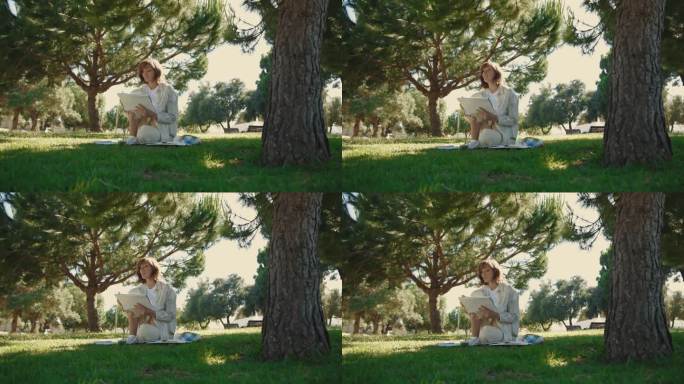 一个成年女子坐在绿色的公园里，一边在速写本上画画，一边聊天