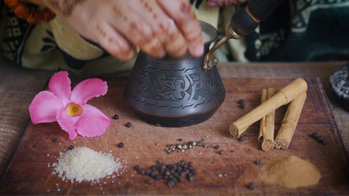 印度妇女用手在制作玛沙拉茶时加入香料。关闭了。