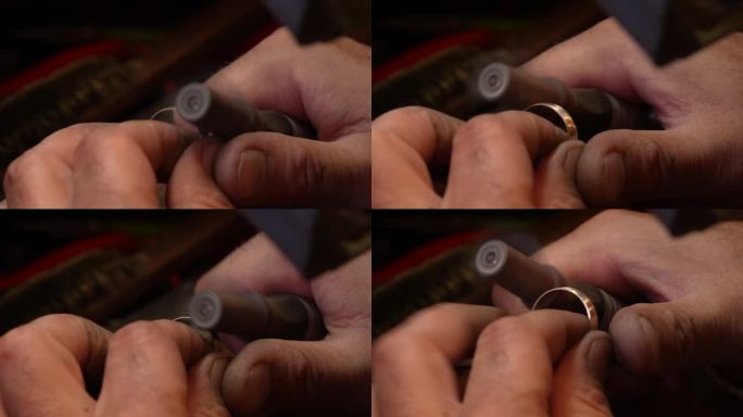 在手工制作金戒指的过程中，珠宝商使用安装在柔性轴钻机上的砂纸卷来打磨金属