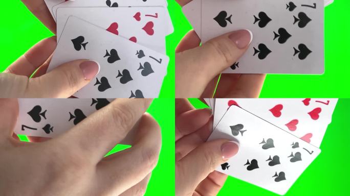 女性的手，法式美甲。女人整理卡片，检查它们，折叠起来，像扇子一样展开四张牌，同样的西装手拿着四张七，