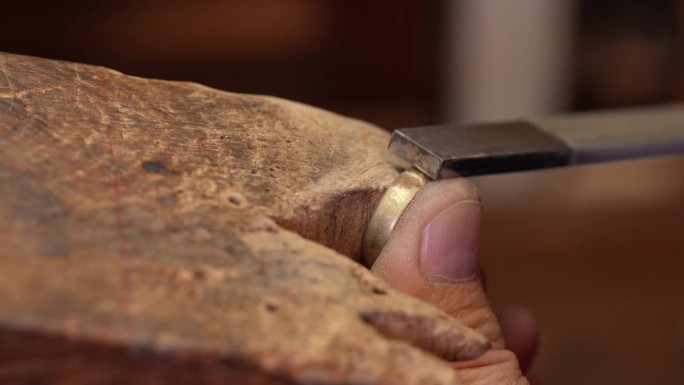金匠珠宝商在工作台上用一把锉刀打磨未完成的戒指