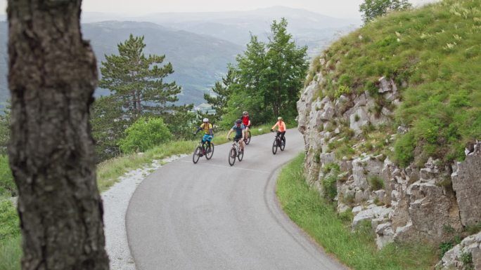 四个山地自行车手骑在柏油山路上