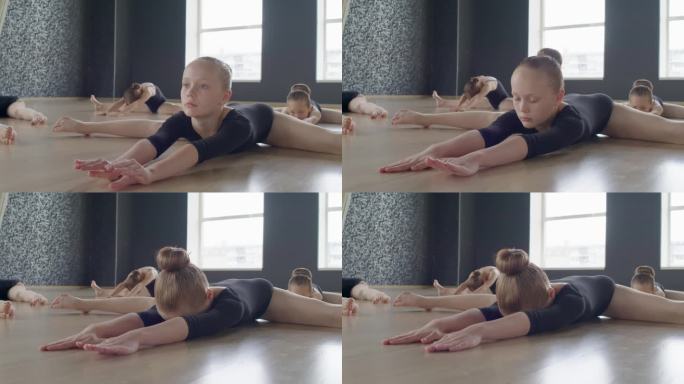 小芭蕾舞演员在地板上做伸展运动