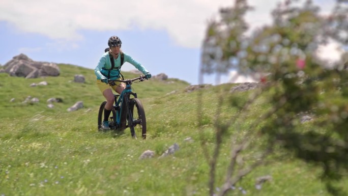 一名女子在阳光下的山上骑着她的电动自行车