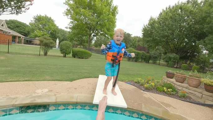 一个成年男子被孩子从跳水板上推下泳池