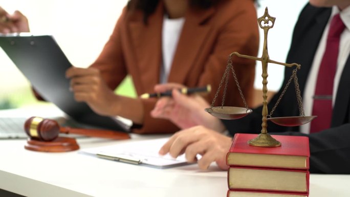 律师办公室桌子上的拍卖锤和律师在法庭上书写文件的近景。