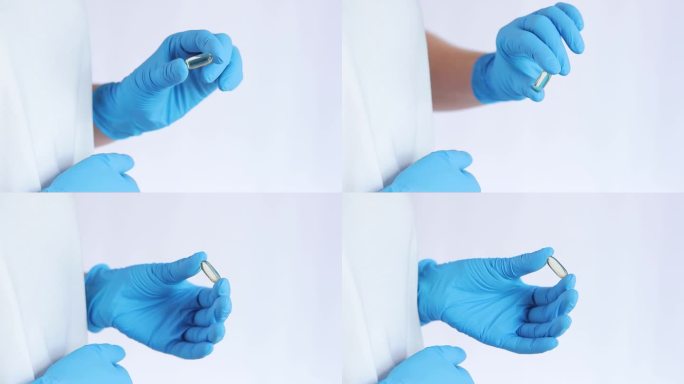 一只戴着蓝色医用乳胶手套的手拿着一个鱼油胶囊。欧米伽- 3