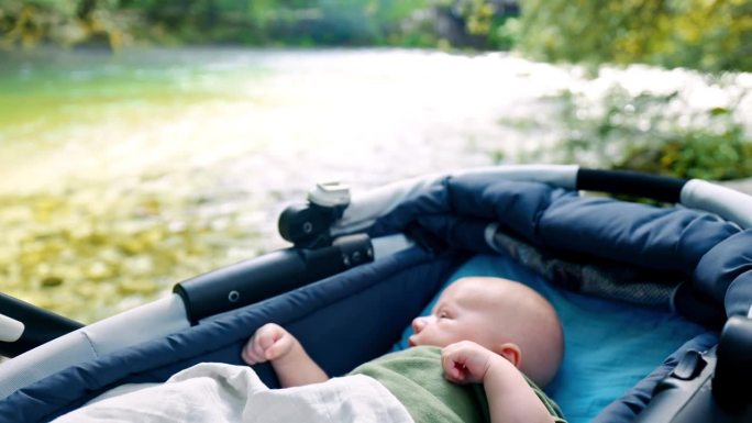 可爱的婴儿在Bohinj湖边的婴儿车里放松
