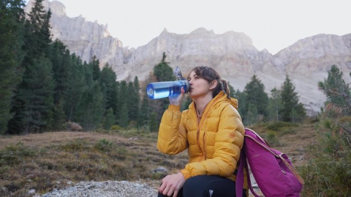 女子在秋天坐在白云石的背景上喝水