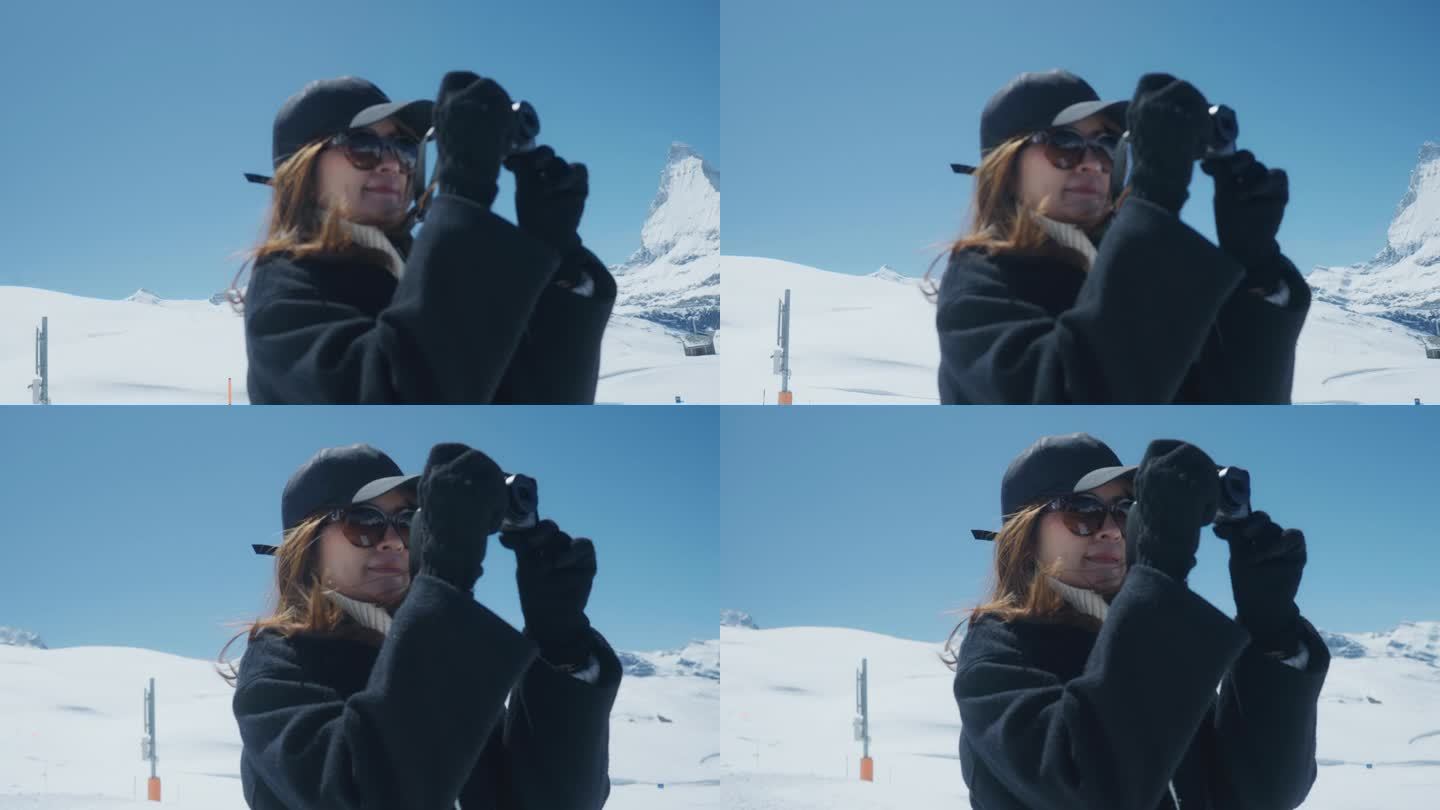 年轻女子在雪山上用数码相机拍照。