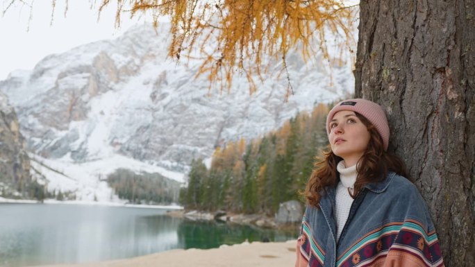 站在布雷斯湖(Lago di Braies)附近的秋天彩色树下的妇女