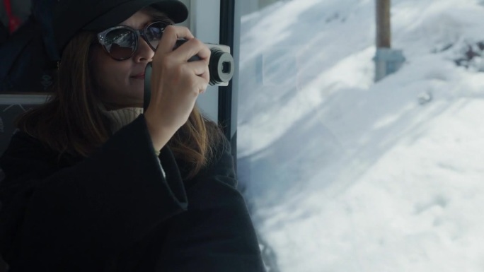 一名亚洲女摄影师在瑞士雪山上的火车上拍摄度假照片。
