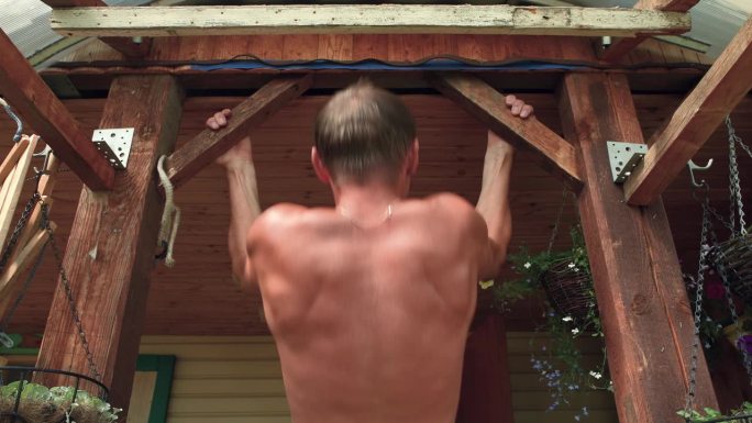 男子在木杆上拉起，锻炼肱二头肌。