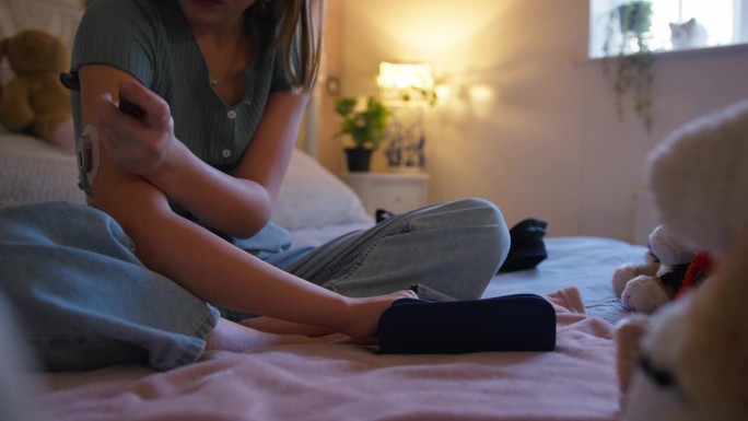 一个年轻的糖尿病女孩坐在家里卧室的床上测量胰岛素水平