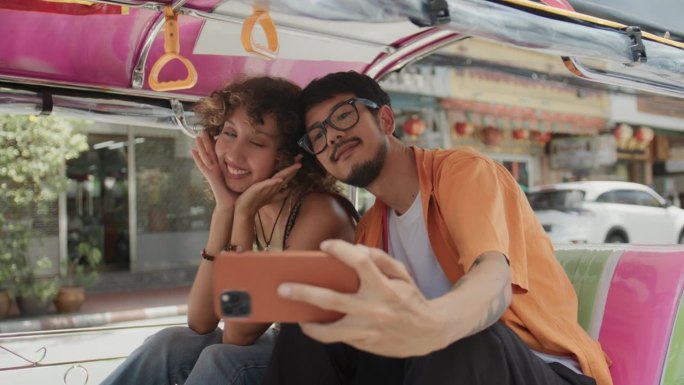 甜蜜的亚洲夫妇在泰国度假，在一辆嘟嘟车出租车上一起享受特殊的时刻和自拍。
