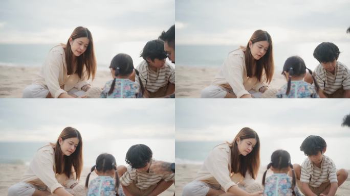 亚洲爱玩的一家人坐在沙滩上堆沙堡，他们在一起消磨时光。