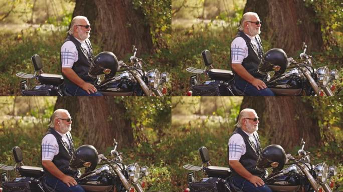 一名年长的白人男性骑摩托车的侧视图，坐在摩托车上，戴着耳机听音乐