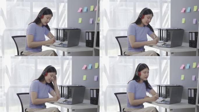 年轻的亚洲女学生戴着耳机在笔记本电脑上上网，同时参加在线课程或讲座，并进行谷歌Zoom视频通话。