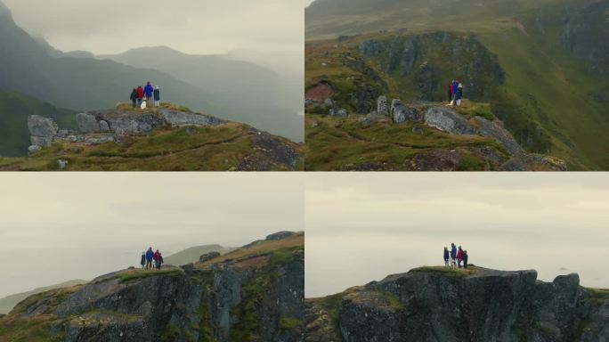 鸟瞰图，年轻的旅行者家庭和一只白狗站在悬崖顶上，看着下面史诗般的北欧景色