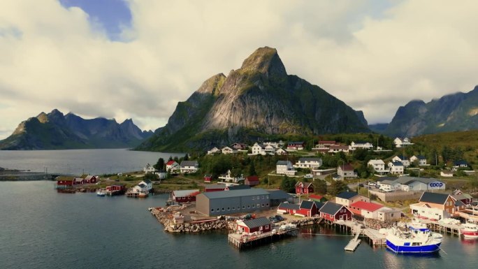 一架无人驾驶飞机飞过挪威渔村的房屋，越过大海，驶向壮丽的岩石峡湾，阳光明媚