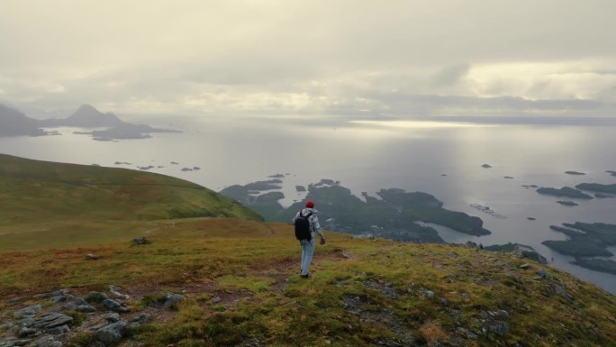 年轻的男性旅行者走向悬崖边缘，欣赏罗弗敦群岛的壮丽景色