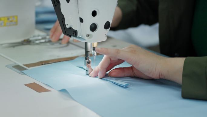 制衣厂女工缝纫工认真缝纫衬衣作业