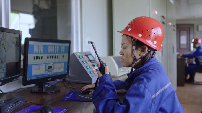 女工程师用电脑和对讲机远程控制机器设备