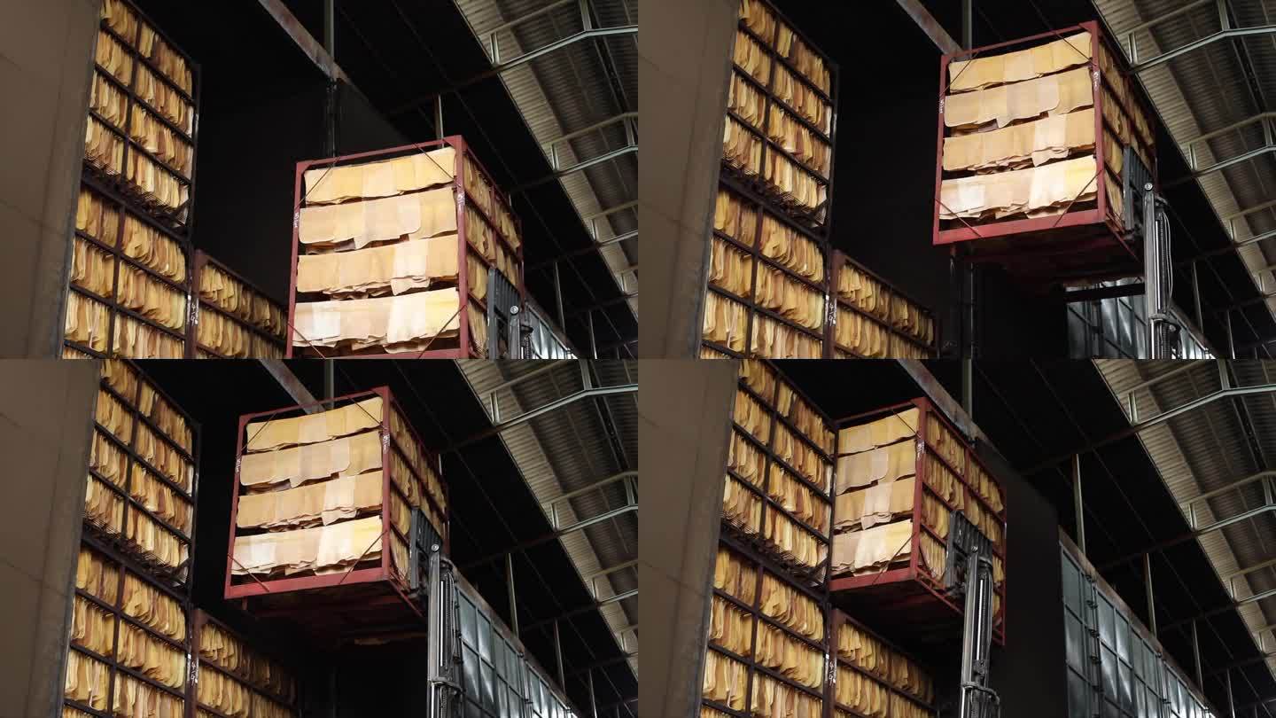在生产过程中，天然橡胶板在工厂砖墙附近的悬挂钢轨上风干。