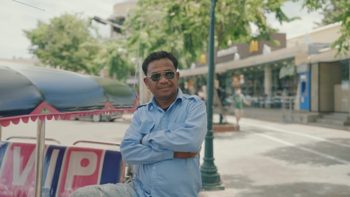 微笑的亚洲老年出租车司机对当地的嘟嘟车充满信心和自豪。