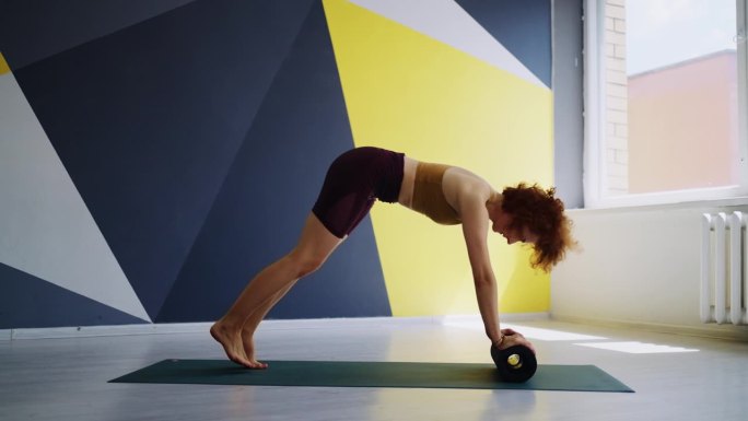 修身女性在现代瑜伽馆训练，女运动员用健身滚筒做运动