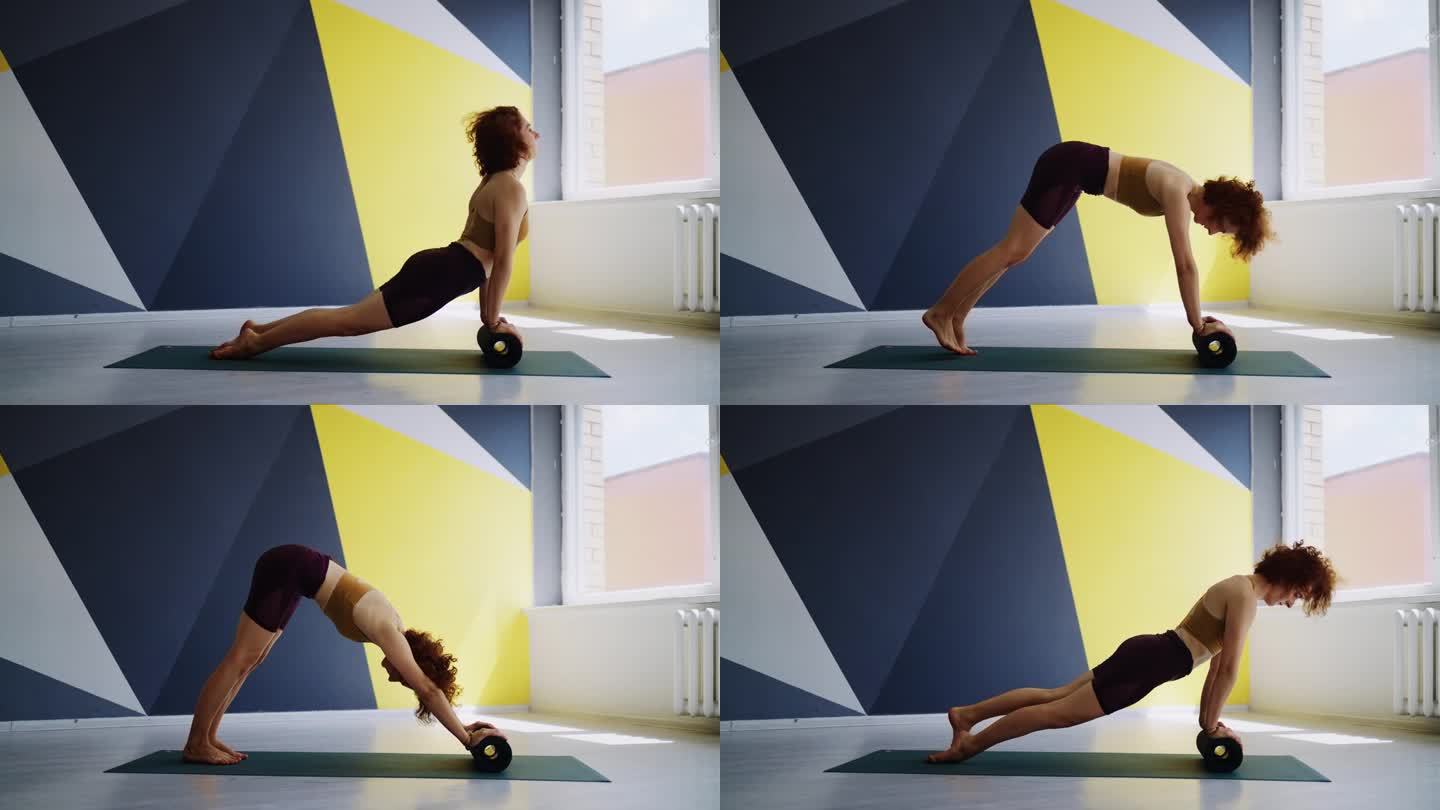 修身女性在现代瑜伽馆训练，女运动员用健身滚筒做运动