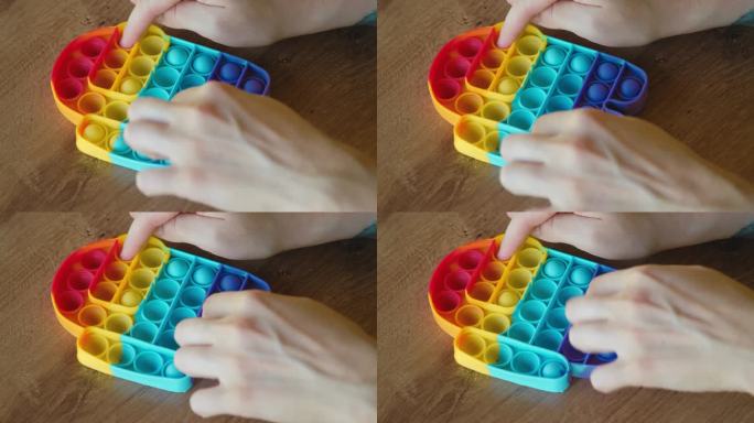 五颜六色的彩虹抗压力感官玩具烦躁推pop在人的手上。年轻女子扮演简单的酒窝。橡胶的色彩斑斓。在儿童和