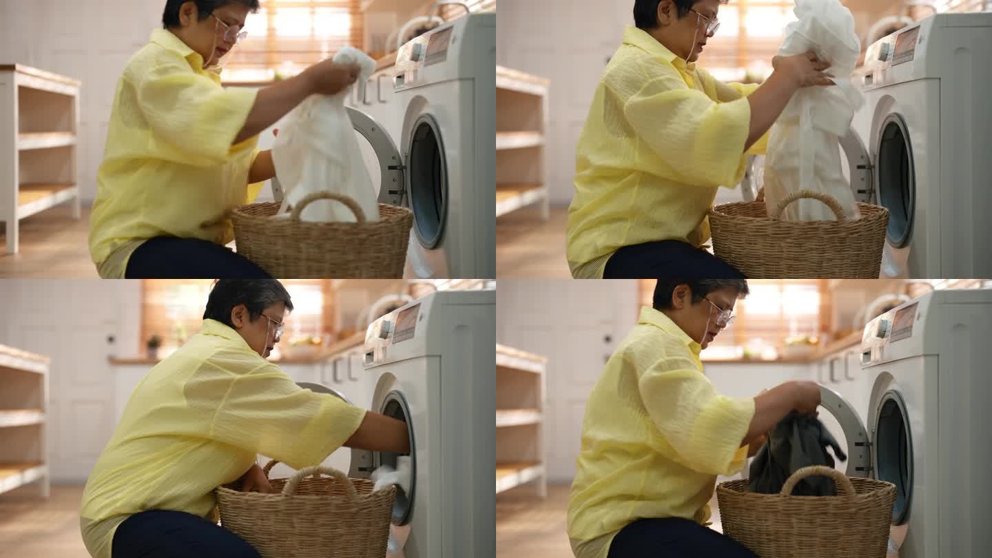 一位亚洲的老祖母正从篮子里拣起衣服放进洗衣机。