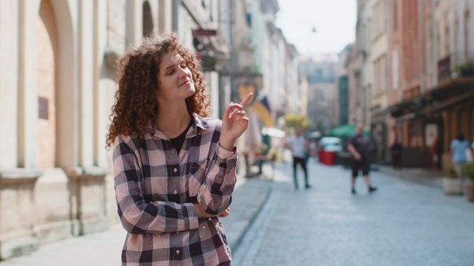 一位若有所思的妇女指着城市街道上商业文字复制空间的空广告区