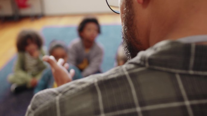 一名男教师正在用数码平板电脑给小学生上课