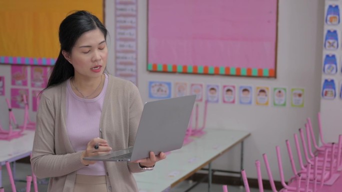年轻的亚裔女老师在学校的白板上写字，在学校的课堂上教学生