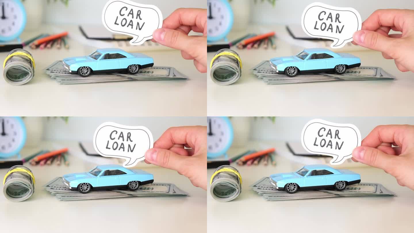 车贷文手里拿着一辆蓝色的小汽车，站在一张白色的桌子上放着钱。汽车保险概念。
