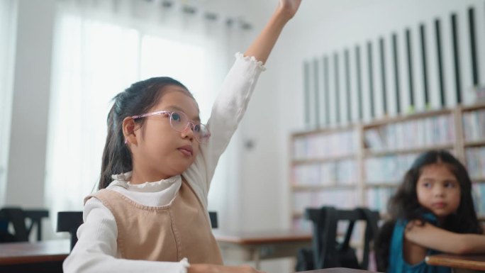 活跃优秀的亚洲学生，戴眼镜的女生，在学校课堂上举手回答问题。图为在学校教室里学习的孩子们。儿童学习理