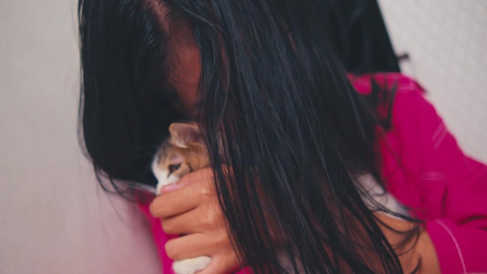 一名亚洲妇女因为受到家人的欺负，在抱着一只猫的时候哭得很伤心
